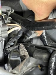 Under the hood, focusing on the area in the firewall where the rubber grommet is, I’ve put my thumb on the tip of the long screwdriver I pushed through from the interior.