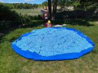 The pool liner, unboxed and rolled out on the grass so that the sun can warm it up