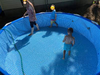 Sharon and two of the boys, in the pool, carefully walking around as it fills up with water