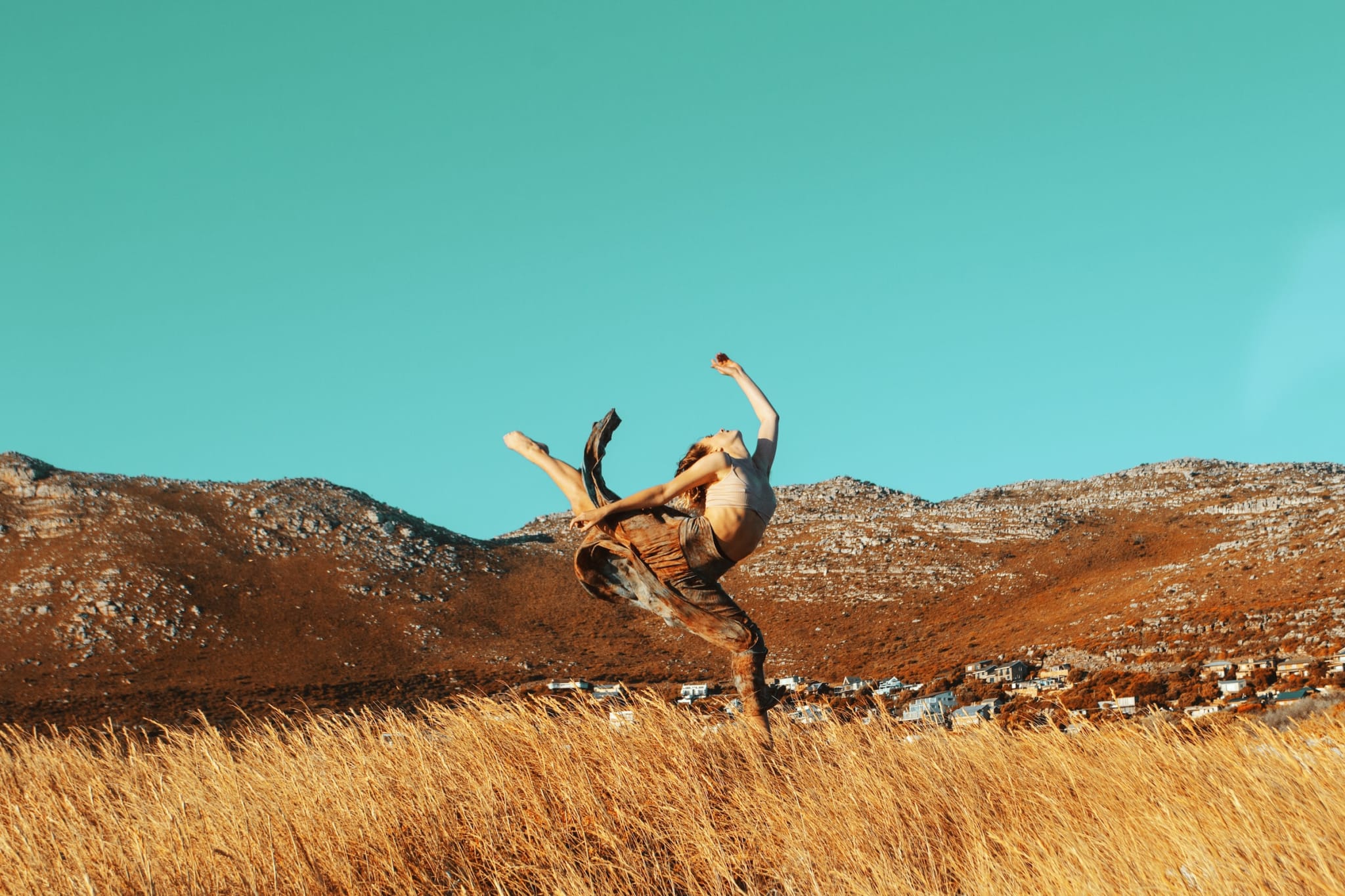 Una persona bailando haciendo una parada de manos en el aire en un campo.