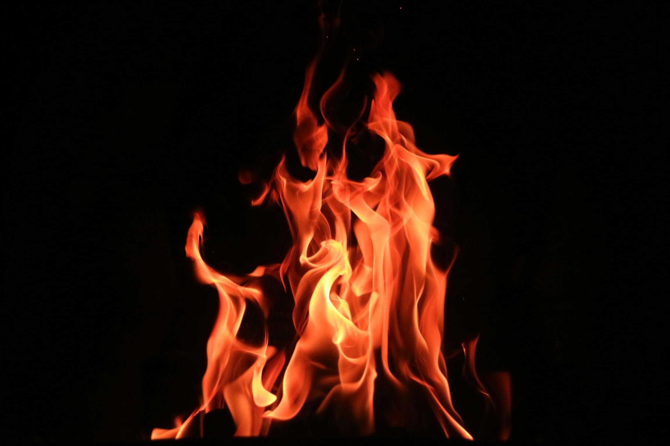 An orange fire blazes against a black background. Photo by 