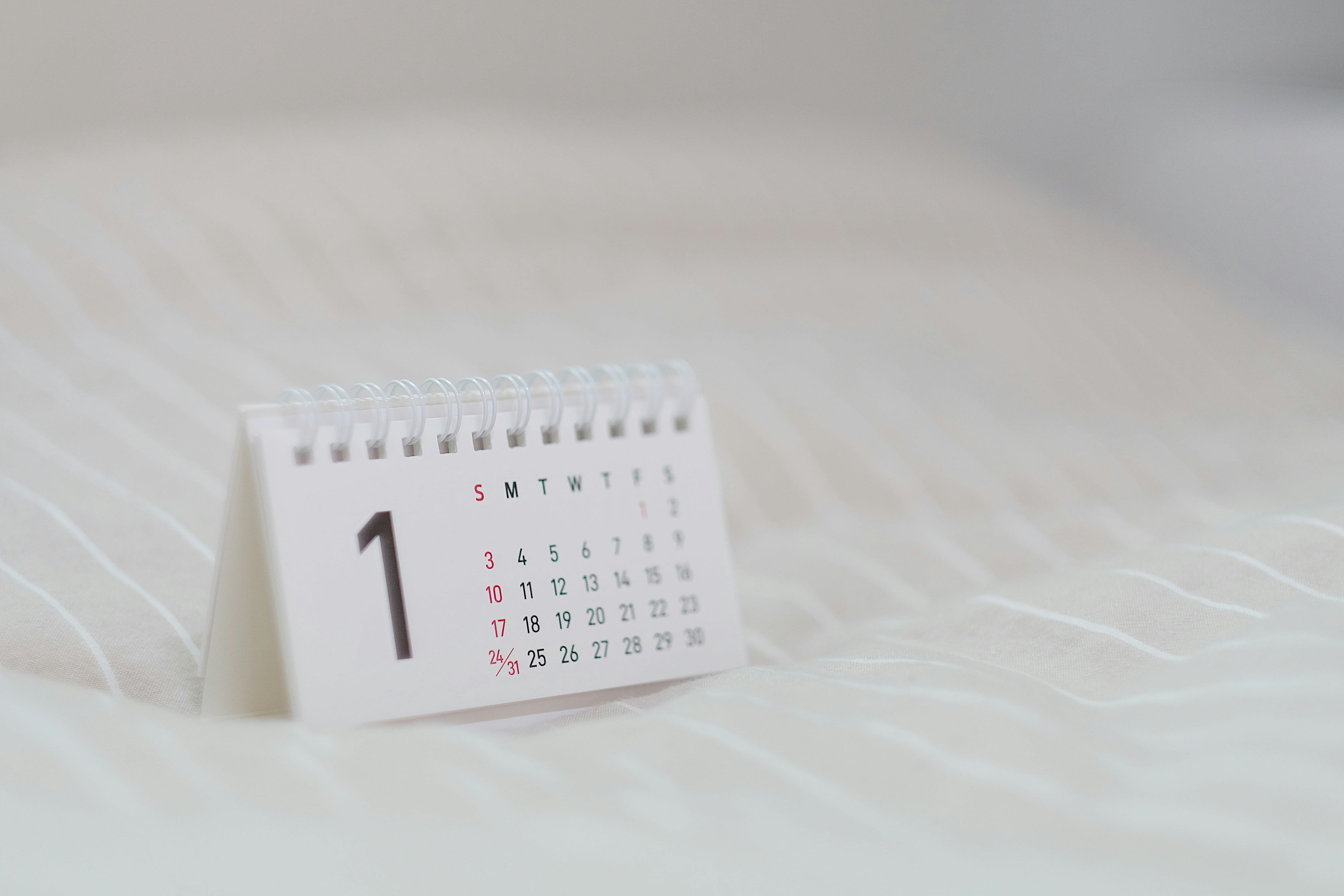 A white calendar with black numbers sitting on a white, gauzy sheet. Image by Kyrie Kim
