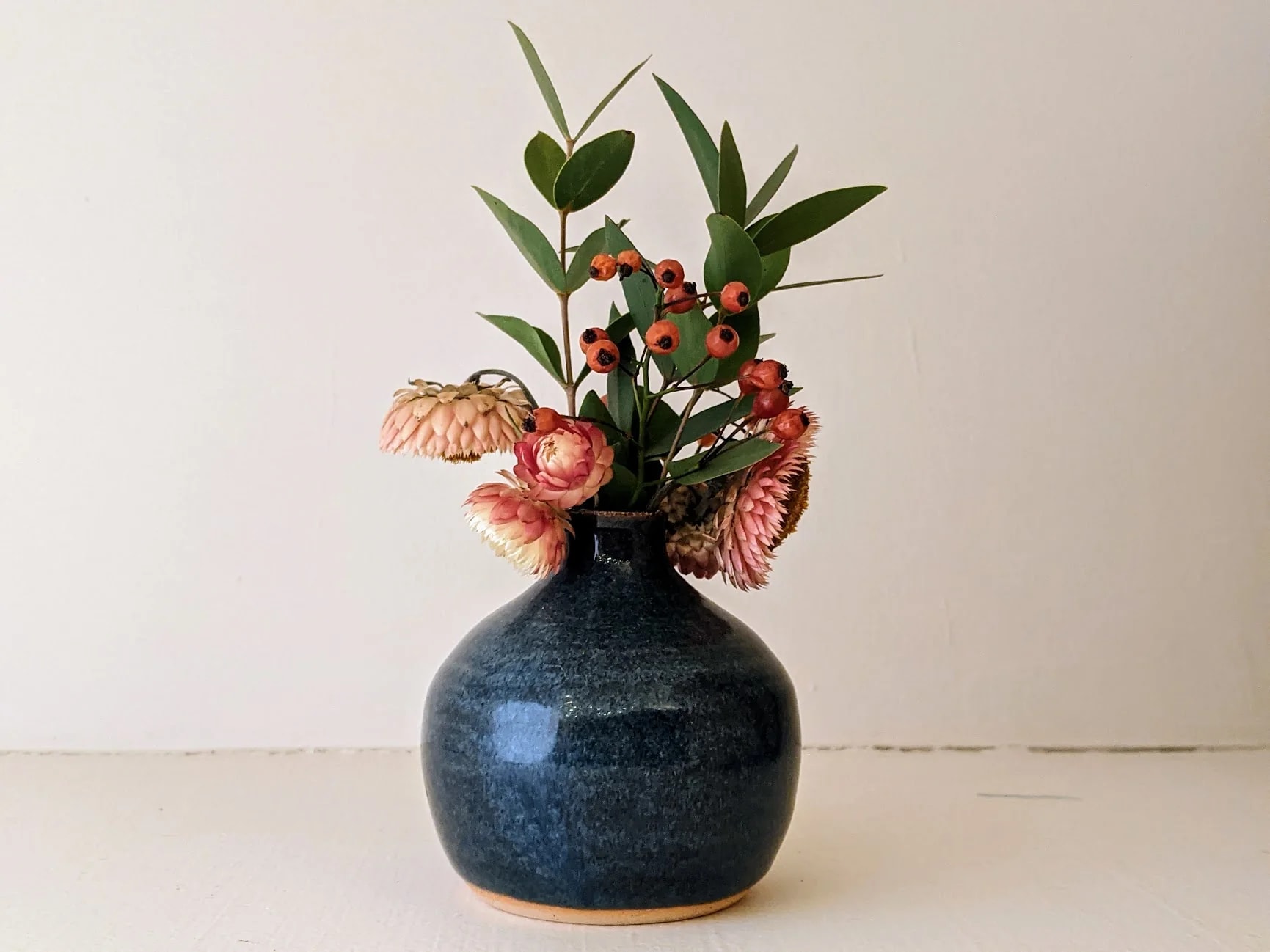Blue bud vase with flowers in it.