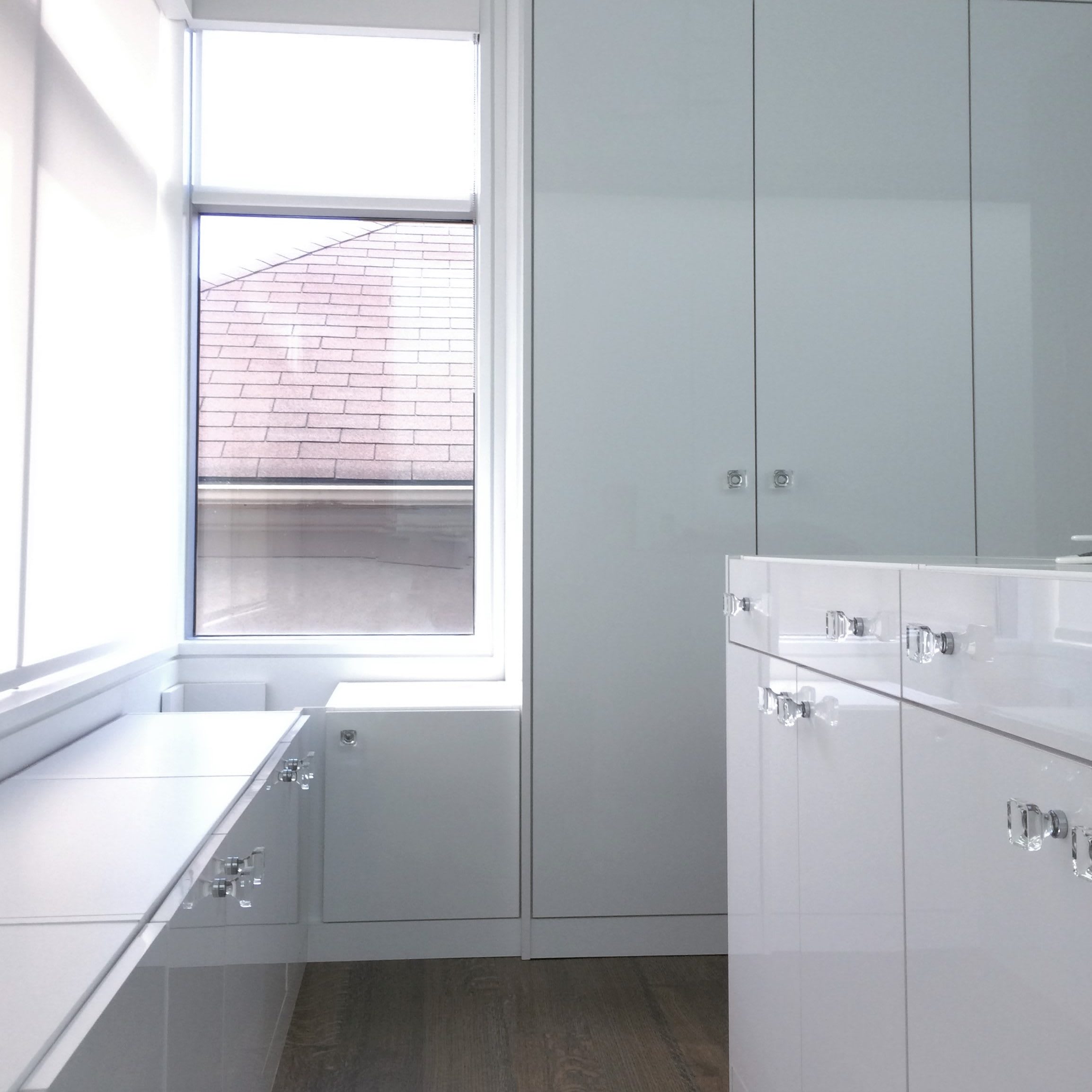 White high-gloss laminate cabinetry with crystal knobs in a walk-in closet