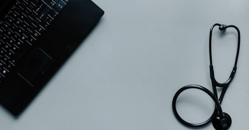 Minimalist image depicting a laptop and stethoscope representing telemedicine and digital health.