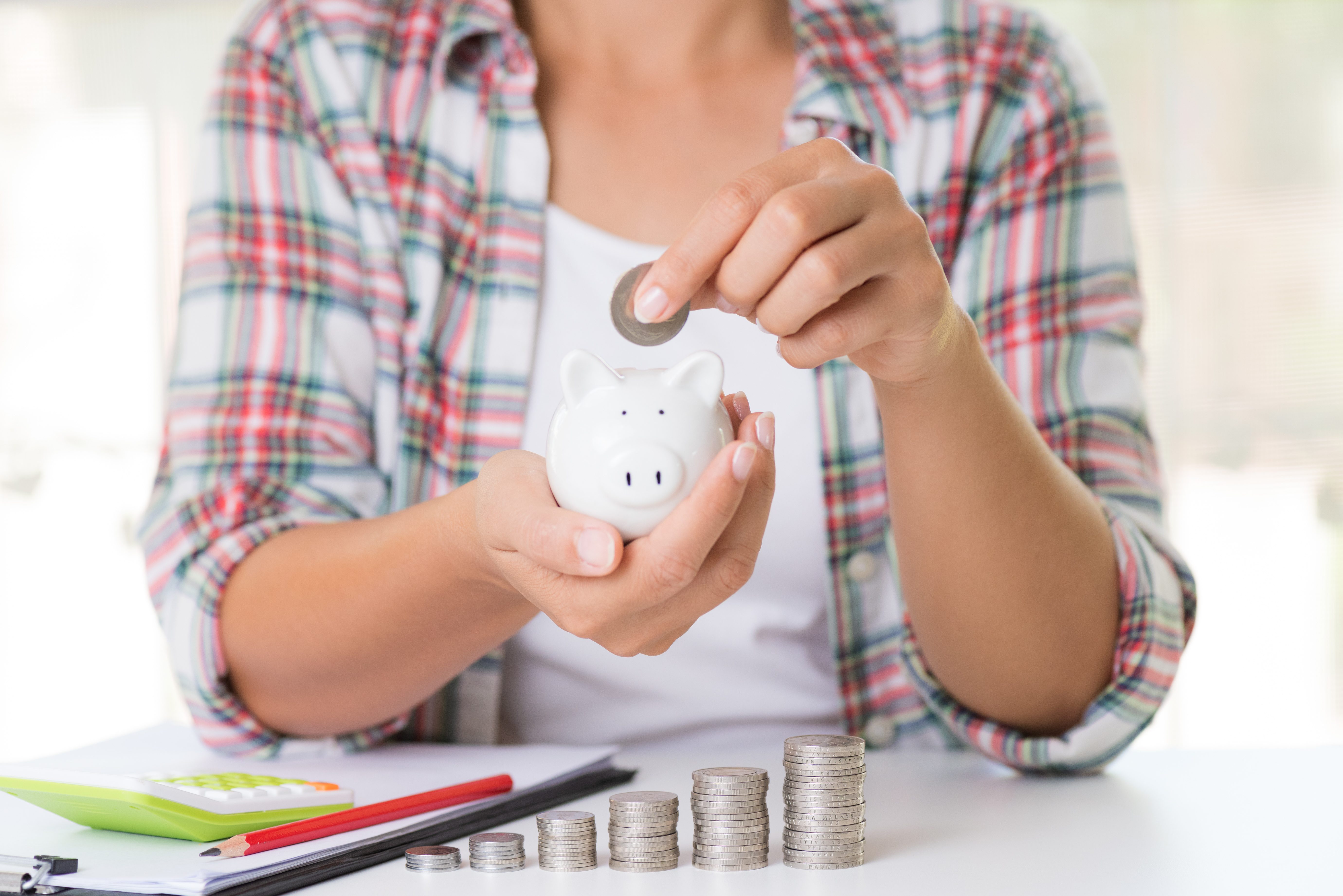 Woman hand putting money coin into piggy bank. Saving money wealth and financial concept.