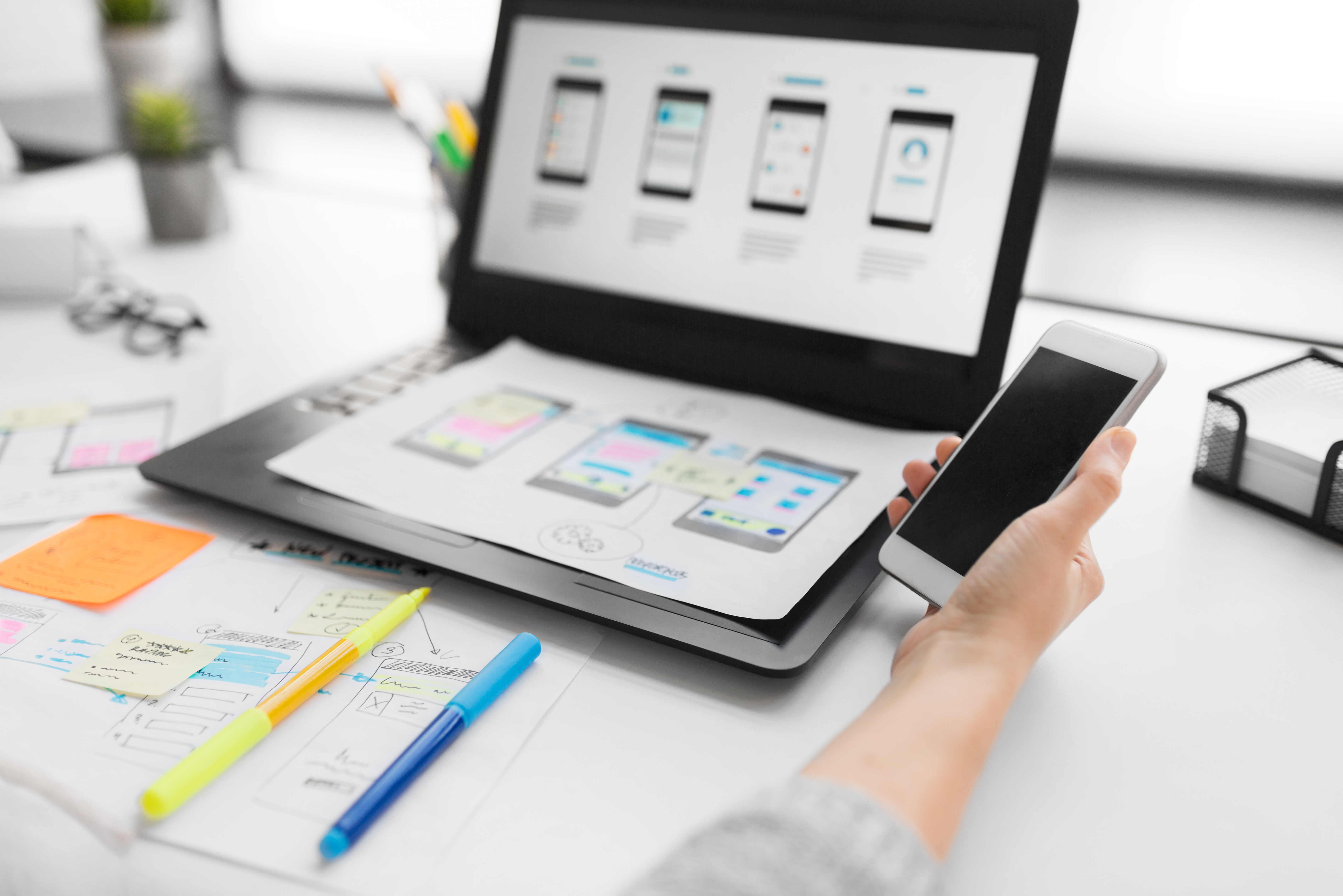 web designer with smartphone and laptop at office
