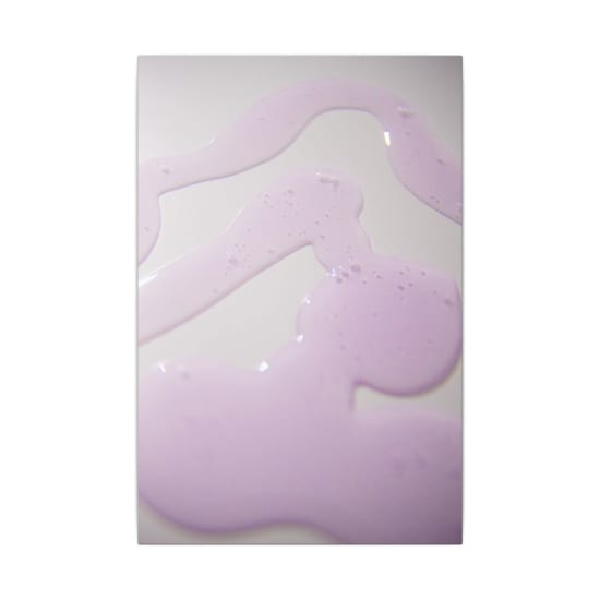 Close-up of purple liquid on white surface creating abstract patterns.