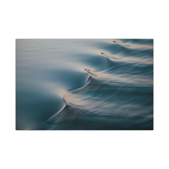 Serene close-up of gentle sea ripples reflecting twilight hues, showcasing fluid motion and tranquility.