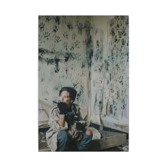 A young boy in an abandoned room with handprints, using a walkie-talkie.