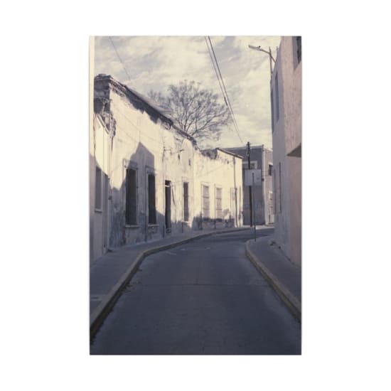 Deserted narrow street with dilapidated buildings and broken windows, capturing urban decay.