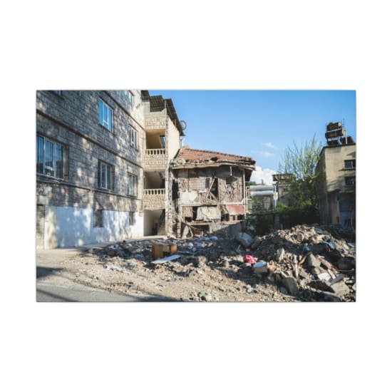 A decaying building amidst urban rubble under a clear sky.