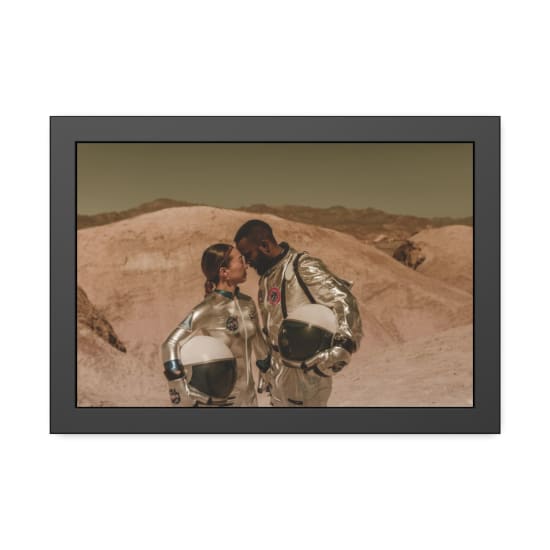 A diverse couple in astronaut suits shares an intimate moment in a desert landscape.