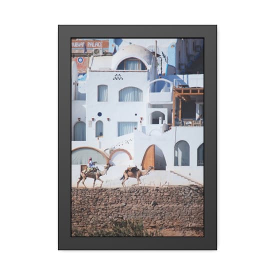 Camels and rider pass by iconic Nubian-style buildings in Luxor, Egypt.