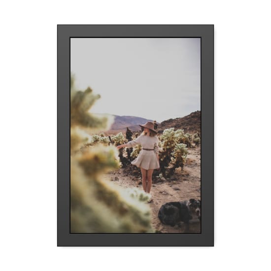 Fashionable woman in desert with dog, amidst cactuses and vast landscape.