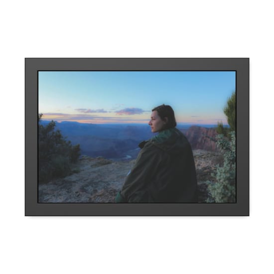 A contemplative woman sitting at the Grand Canyon rim during sunset, capturing a serene outdoor moment.