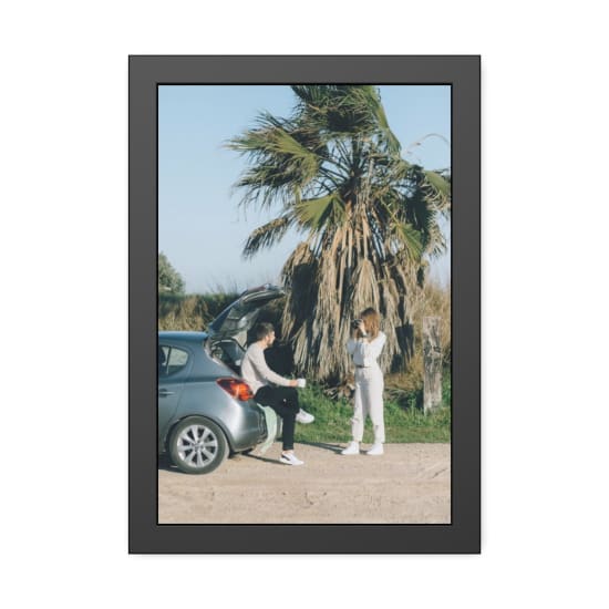 A couple enjoys a road trip, capturing moments near a palm tree outdoors.