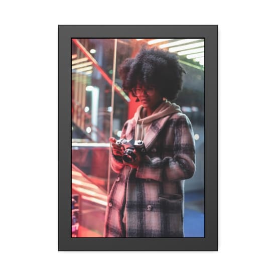 Stylish woman in coat holding camera against neon lights, captured in urban setting.