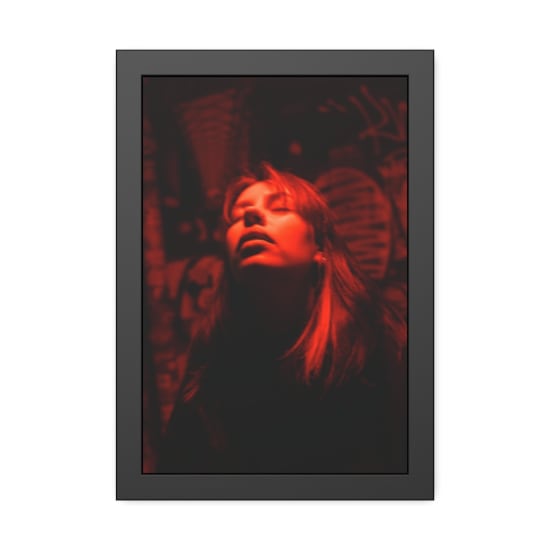 Moody portrait of a woman under red lighting against graffiti backdrop.