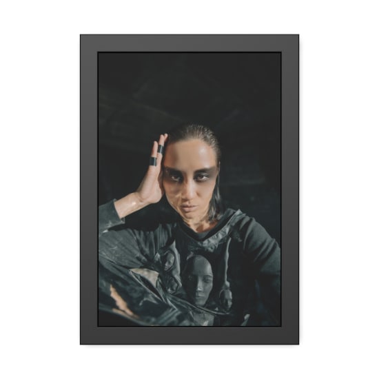 A woman poses dramatically with dark, cyberpunk-style makeup and futuristic attire.