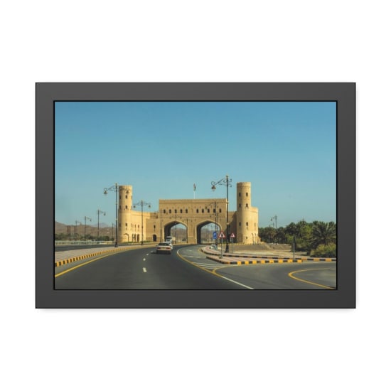 A traditional Omani gateway viewed from the road under clear blue skies.