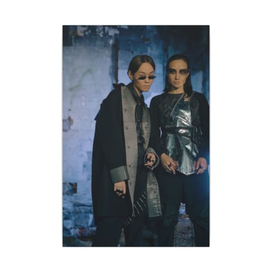 Two models in futuristic fashion posing in an industrial setting.