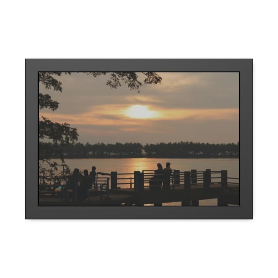 A peaceful sunset scene with silhouettes by a lake, creating a warm and serene atmosphere.