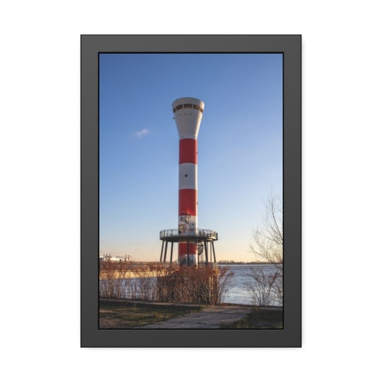 A striking lighthouse towers over the Elbe river under a clear blue sky in Hamburg.