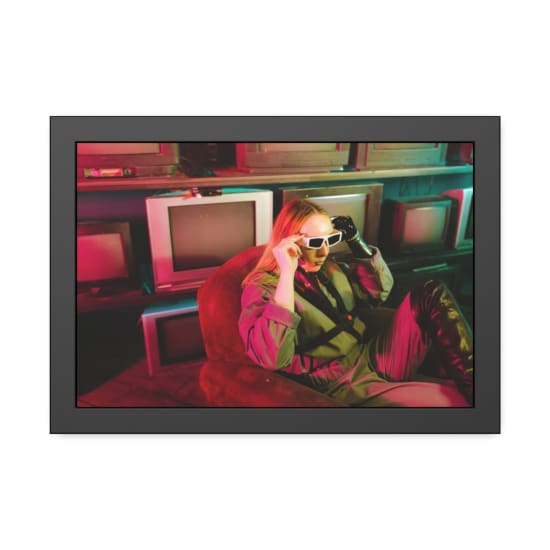 A woman in futuristic attire poses with vintage TVs under neon lights.