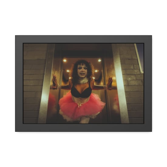 A person in clown makeup and tutu costume emerging from an elevator, showcasing gothic and horror aesthetics.