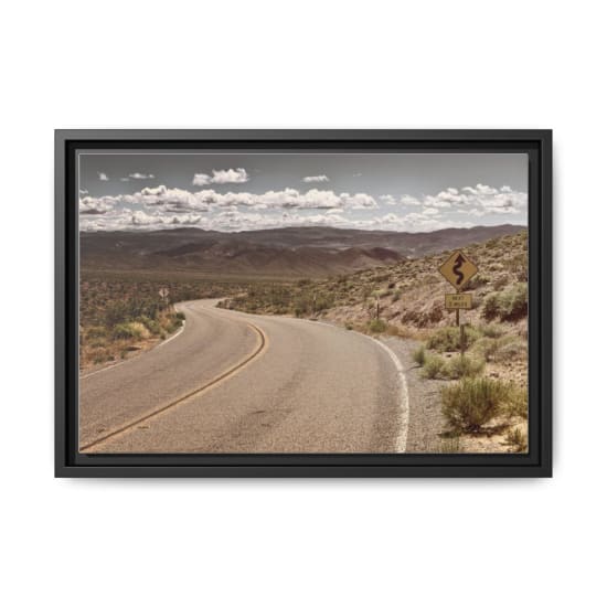 Curved desert road in arid landscape with mountains and clear sky