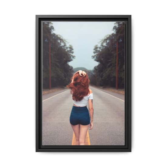 Red-haired woman in jean shorts walking down a forest road, showcasing style and freedom.