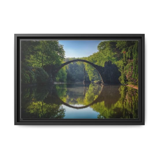 Capture of the iconic Rakotzbrücke reflecting in calm waters amidst lush greenery in Germany.