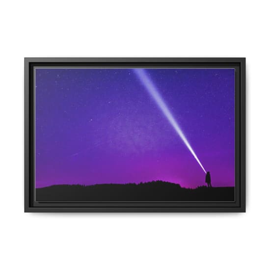 Silhouette of a person shining a flashlight under a starry violet night sky, creating a dramatic scene.