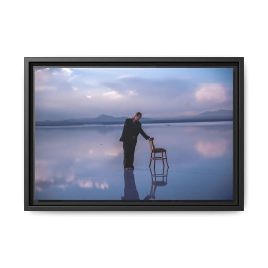 Serene scene of a woman standing on a dreamy salt flat reflecting the sky, with a chair as a prop.