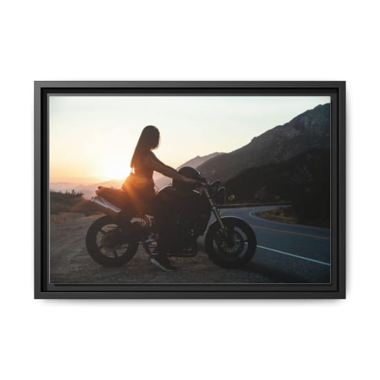 Woman on a motorcycle at sunset on a scenic mountain road.