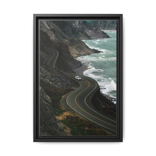 A white car navigating a winding road along a stunning coastal landscape.