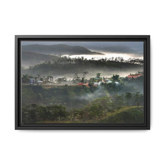 Scenic view of misty mountains and pine trees at dawn with a red vehicle on a winding road.