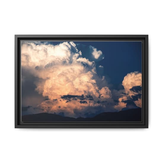 Dramatic cumulus clouds illuminate the sky at sunset over Spanish mountains.