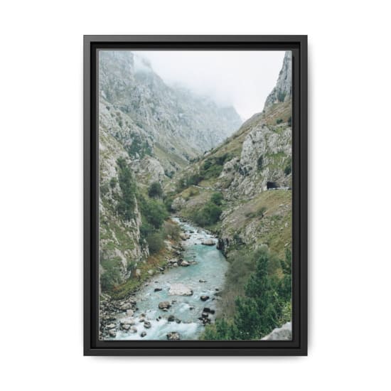 Beautiful misty mountain gorge with a flowing river through lush greenery.