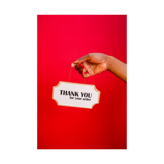 A hand holding a thank you sign against a vibrant red background, ideal for gratitude themes.
