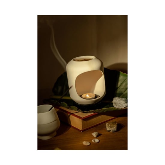 A soothing aromatherapy scene with a lit candle, crystals, and a book, perfect for relaxation.