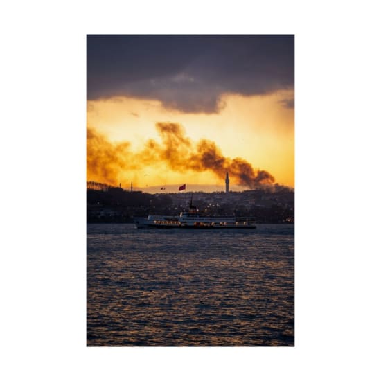 A ferry sails across the Bosphorus at sunset with Istanbul's skyline in the background.