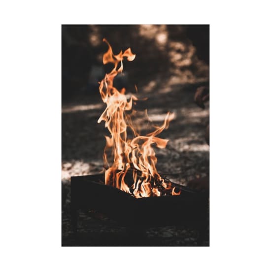 A vibrant campfire with tall flames in a grill setting outdoors.