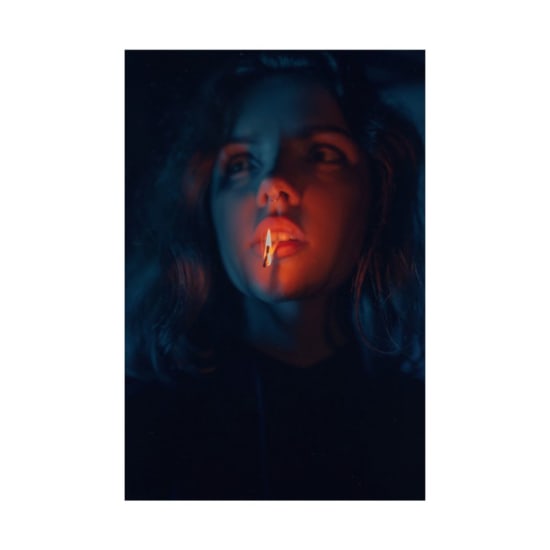 Eerie portrait of a woman illuminated by a matchstick flame in dark tones.