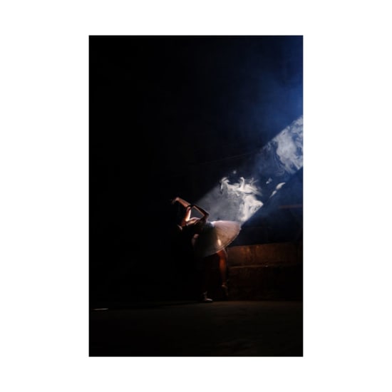 A ballerina gracefully dances in a spotlight with dramatic lighting effects.