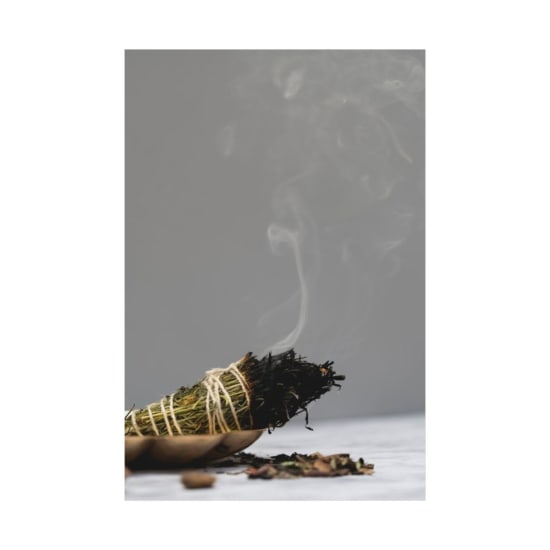Close-up of aromatic incense stick burning, releasing a gentle smoke trail against a neutral background.