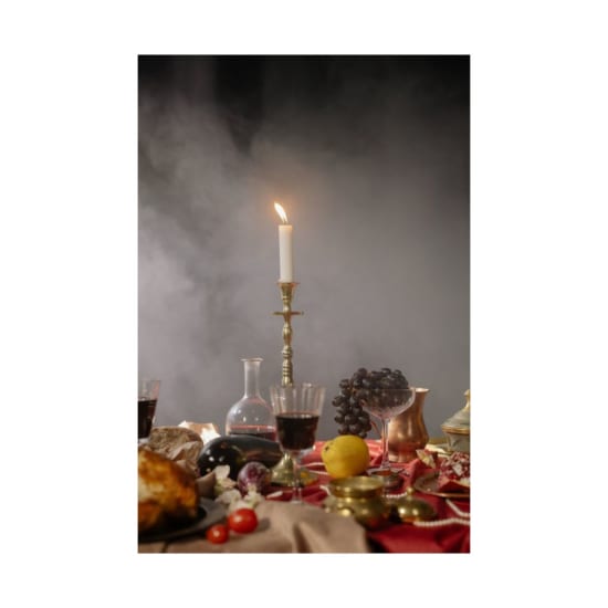 Artistic still life featuring candlelight, black grapes, and a wine setting in a Renaissance style.