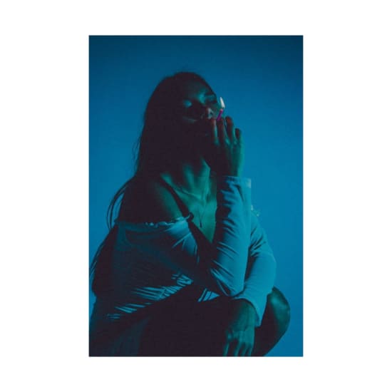 Silhouetted woman smoking in a blue-toned studio, capturing a moody atmosphere.