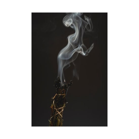 Ethereal smoke swirls from burning incense, creating a mystical ambiance against a dark background.
